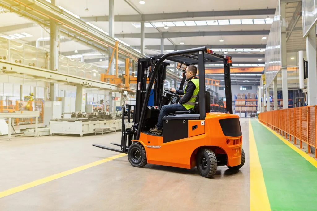 Storehouse employee in uniform working on forklift in modern automatic warehouse